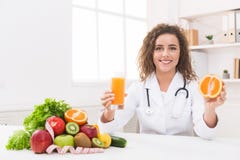 Femme de nutritionniste avec le jus d'orange et l'orange au bureau image libre de droits Femme de nutritionniste avec le jus d'orange et l'orange au bureau image libre de droits