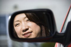 Femme de sourire dans le miroir de véhicule Image libre de droits Femme de sourire dans le miroir de véhicule Image libre de droits
