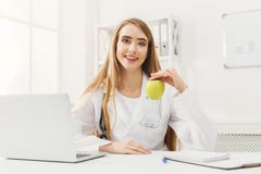 Femme de sourire de nutritionniste avec la pomme au bureau photographie stock Femme de sourire de nutritionniste avec la pomme au bureau photographie stock