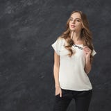 Femme de sourire posant sur le fond gris images stock Femme de sourire posant sur le fond gris images stock