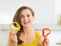 Femme de sourire tenant deux tranches de paprika rouge et jaune Photos libres de droits Femme de sourire tenant deux tranches de paprika rouge et jaune Photos libres de droits
