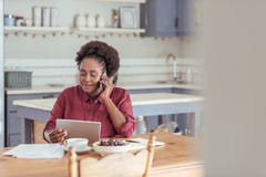 Femme de sourire à l'aide d'un comprimé et parlant au téléphone Photographie stock