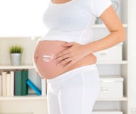 Femme enceinte appliquant la crème de lotion Images libres de droits Femme enceinte appliquant la crème de lotion Images libres de droits
