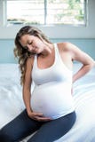 Femme enceinte avec la séance de douleurs de dos Photos libres de droits Femme enceinte avec la séance de douleurs de dos Photos libres de droits