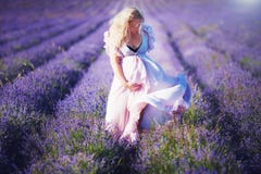 Femme enceinte de jeunes dans la robe légère marchant par le gisement de lavande images libres de droits Femme enceinte de jeunes dans la robe légère marchant par le gisement de lavande images libres de droits