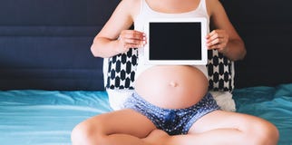 Femme enceinte montrant l'écran numérique vide de comprimé Photographie stock libre de droits Femme enceinte montrant l'écran numérique vide de comprimé Photographie stock libre de droits