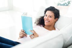 Femme enceinte souriant tandis que livre de lecture Image libre de droits Femme enceinte souriant tandis que livre de lecture Image libre de droits