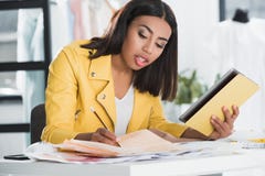 Femme focalisée à l'aide du comprimé numérique tout en travaillant dans le studio de conception d'habillement images stock Femme focalisée à l'aide du comprimé numérique tout en travaillant dans le studio de conception d'habillement images stock