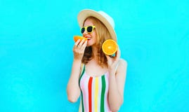 Femme heureuse de portrait d'?t? se tenant dans des ses mains et mangeant des tranches de fruit orange dans le chapeau de paille image libre de droits Femme heureuse de portrait d'?t? se tenant dans des ses mains et mangeant des tranches de fruit orange dans le chapeau de paille image libre de droits