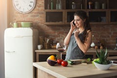 Femme heureuse parlant au téléphone dans la cuisine à la maison image libre de droits Femme heureuse parlant au téléphone dans la cuisine à la maison image libre de droits