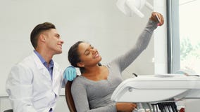 Femme heureuse prenant un selfie avec son dentiste à l'aide du téléphone intelligent image stock Femme heureuse prenant un selfie avec son dentiste à l'aide du téléphone intelligent image stock
