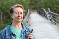 Femme mûre attendant votre appel S'habillant dans une veste de denim, une dame caucasienne supérieure se tient prêt le pont de ri Photo libre de droits Femme mûre attendant votre appel S'habillant dans une veste de denim, une dame caucasienne supérieure se tient prêt le pont de ri Photo libre de droits