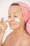Femme mûre attirante avec la crème sur le visage Images libres de droits Femme mûre attirante avec la crème sur le visage Images libres de droits