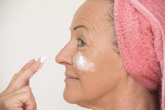 Femme mûre mettant la crème sur le visage Image libre de droits Femme mûre mettant la crème sur le visage Image libre de droits