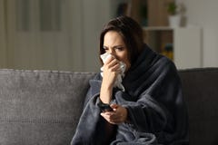 Femme malade soufflant et regardant la TV à la maison photo libre de droits Femme malade soufflant et regardant la TV à la maison photo libre de droits