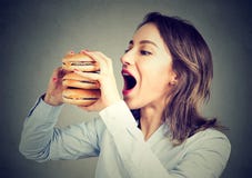 Femme mangeant implorant un double hamburger photo libre de droits Femme mangeant implorant un double hamburger photo libre de droits