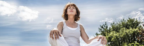 Femme rayonnante du yoga 50s cherchant pour l'équilibre spirituel, angle faible photo libre de droits Femme rayonnante du yoga 50s cherchant pour l'équilibre spirituel, angle faible photo libre de droits