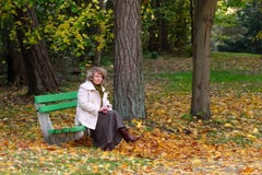 Femme s'asseyant sur un banc en stationnement image stock Femme s'asseyant sur un banc en stationnement image stock