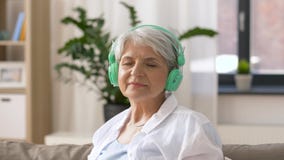 Femme supérieure dans des écouteurs écoutant la musique banque de vidéos Femme supérieure dans des écouteurs écoutant la musique banque de vidéos