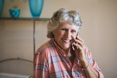 Femme supérieure de sourire parlant au téléphone à la maison photos libres de droits Femme supérieure de sourire parlant au téléphone à la maison photos libres de droits