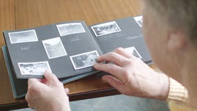 Femme supérieure regardant par le vieil album de photographie Femme supérieure regardant par le vieil album de photographie