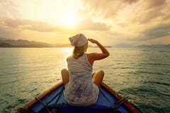 Femme voyageant en bateau au coucher du soleil parmi les îles photo libre de droits Femme voyageant en bateau au coucher du soleil parmi les îles photo libre de droits