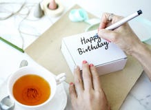 Femme écrivant le joyeux anniversaire sur un boîtier blanc Images stock Femme écrivant le joyeux anniversaire sur un boîtier blanc Images stock