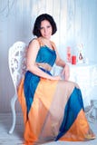 Femme élégante dans une robe lumineuse à la table photographie stock libre de droits Femme élégante dans une robe lumineuse à la table photographie stock libre de droits