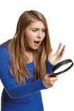 Femme étonnée regardant par la loupe images stock Femme étonnée regardant par la loupe images stock