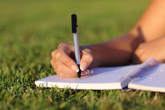 Fermez-vous d'une écriture de main de femme sur un carnet extérieur photo libre de droits Fermez-vous d'une écriture de main de femme sur un carnet extérieur photo libre de droits