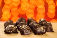 Fermez-vous de frais, délicieux et les bonbons crus faits maison sains de chocolat avec d'or arrose sur le fond brouillé rouge av image libre de droits Fermez-vous de frais, délicieux et les bonbons crus faits maison sains de chocolat avec d'or arrose sur le fond brouillé rouge av image libre de droits