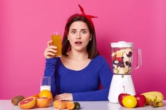 Fermez-vous de la femme de brune avec le verre de jus d'orange frais à disposition Madame aime la consommation saine, faisant le photo libre de droits Fermez-vous de la femme de brune avec le verre de jus d'orange frais à disposition Madame aime la consommation saine, faisant le photo libre de droits