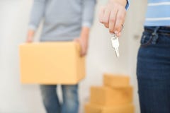 Fermez-vous de la main tenant une clé tandis qu'un homme tenant une boîte pour se déplacer photographie stock libre de droits Fermez-vous de la main tenant une clé tandis qu'un homme tenant une boîte pour se déplacer photographie stock libre de droits