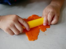 Fermez-vous des mains du petit bébé roulant sur le playdough sur le plancher de maison image libre de droits Fermez-vous des mains du petit bébé roulant sur le playdough sur le plancher de maison image libre de droits
