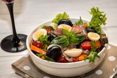 Fermez-vous, macro Dîner français servi avec le vin rouge Salade traditionnelle de nicoise de niçoise dans un plat blanc sur une image stock Fermez-vous, macro Dîner français servi avec le vin rouge Salade traditionnelle de nicoise de niçoise dans un plat blanc sur une image stock