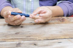 Fermez-vous utilisant le lancelet sur le doigt à vérifier le taux du sucre dans le sang par le mètre de glucose images libres de droits Fermez-vous utilisant le lancelet sur le doigt à vérifier le taux du sucre dans le sang par le mètre de glucose images libres de droits