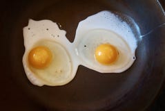 Fermez-vous vers le haut de deux oeufs au plat sur le fond noir de casserole photos stock Fermez-vous vers le haut de deux oeufs au plat sur le fond noir de casserole photos stock