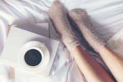Fermez-vous vers le haut des femmes de jambes sur le lit blanc Le livre de lecture de femmes et le café potable dans le matin dét images stock Fermez-vous vers le haut des femmes de jambes sur le lit blanc Le livre de lecture de femmes et le café potable dans le matin dét images stock