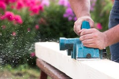 Fermez-vous vers le haut des mains de charpentier fonctionnant avec la planeuse électrique sur la planche en bois images stock Fermez-vous vers le haut des mains de charpentier fonctionnant avec la planeuse électrique sur la planche en bois images stock