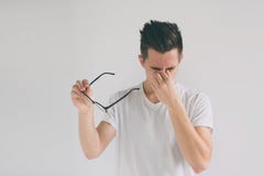 Fermez-vous vers le haut du portrait d'un homme attirant avec des lunettes Le pauvre jeune type a des problèmes de vue Il frotte photos libres de droits Fermez-vous vers le haut du portrait d'un homme attirant avec des lunettes Le pauvre jeune type a des problèmes de vue Il frotte photos libres de droits