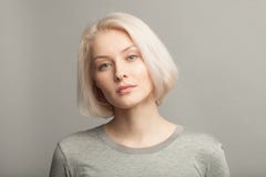 Fermez-vous vers le haut du portrait de la jeune belle femme blonde sur le backgr gris Photo stock Fermez-vous vers le haut du portrait de la jeune belle femme blonde sur le backgr gris Photo stock