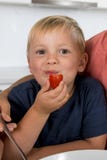 Fermez-vous vers le haut du portrait des jeunes pendant 3 années de garçon avec sa cuisine de mère à la maison mangeant apprécier photographie stock libre de droits Fermez-vous vers le haut du portrait des jeunes pendant 3 années de garçon avec sa cuisine de mère à la maison mangeant apprécier photographie stock libre de droits