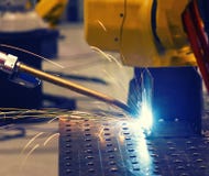 Fermez-vous vers le haut du robot industriel jaune soudant la partie des véhicules à moteur dans l'usine moderne, modifiée la ton photo stock Fermez-vous vers le haut du robot industriel jaune soudant la partie des véhicules à moteur dans l'usine moderne, modifiée la ton photo stock