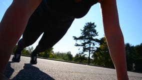 Fermez-vous vers le haut du tir de la jeune femme faisant des pousées dehors banque de vidéos Fermez-vous vers le haut du tir de la jeune femme faisant des pousées dehors banque de vidéos