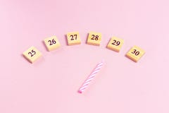 Festive candle for birthday cake indicates age on wooden cubes on pink background