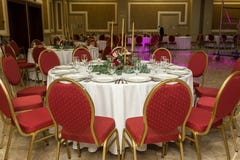 Festively dekorerad rund banketttabell i restaurangen Nya blommor ?r guld- stearinljus och r?da stolar dyrt rikt fotografering för bildbyråer Festively dekorerad rund banketttabell i restaurangen Nya blommor ?r guld- stearinljus och r?da stolar dyrt rikt fotografering för bildbyråer