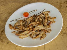 Fette fritte croccanti della carne di maiale in un piatto bianco su un fondo di legno fotografia stock Fette fritte croccanti della carne di maiale in un piatto bianco su un fondo di legno fotografia stock