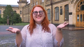 Fettes Ingwermädchen mit Gläsern geht in Park unter den Regen und hebt die Hände an, aufgeregt über Regen, Inspirationskonzept stock video Fettes Ingwermädchen mit Gläsern geht in Park unter den Regen und hebt die Hände an, aufgeregt über Regen, Inspirationskonzept stock video