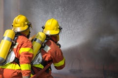 2 Feuerwehrmänner, die Wasser in der Feuerbekämpfungsoperation sprühen lizenzfreie stockfotos 2 Feuerwehrmänner, die Wasser in der Feuerbekämpfungsoperation sprühen lizenzfreie stockfotos
