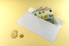 A few Euro bills are in an envelope. Three Euro coins lie on a yellow background stock images A few Euro bills are in an envelope. Three Euro coins lie on a yellow background stock images
